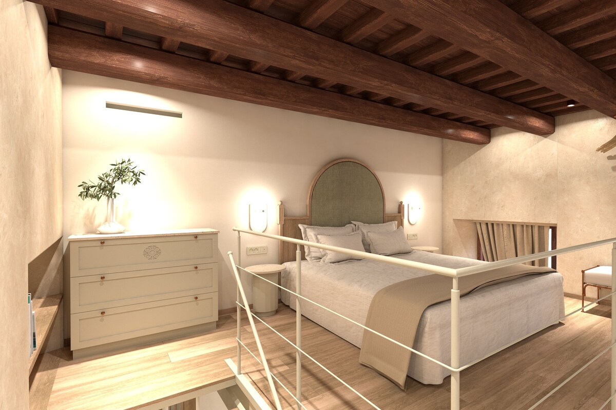 A bedroom with a bed, bedside table, lamp, and a view of the outdoors.