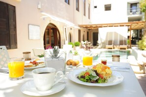 A breakfast table with a plate of food, a glass of orange juice, and a cup of coffee. - Pepi Boutique Hotel - Adults Only (Rethymno)