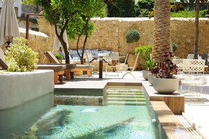 Una piscina al aire libre, sombrillas, sillones reclinables de piscina