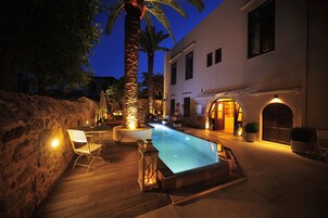 Una piscina al aire libre, sombrillas, sillones reclinables de piscina