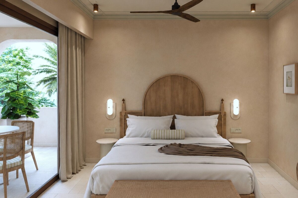 Un dormitorio con cama, mesitas de noche, ventilador de techo y vistas al verdor exterior.