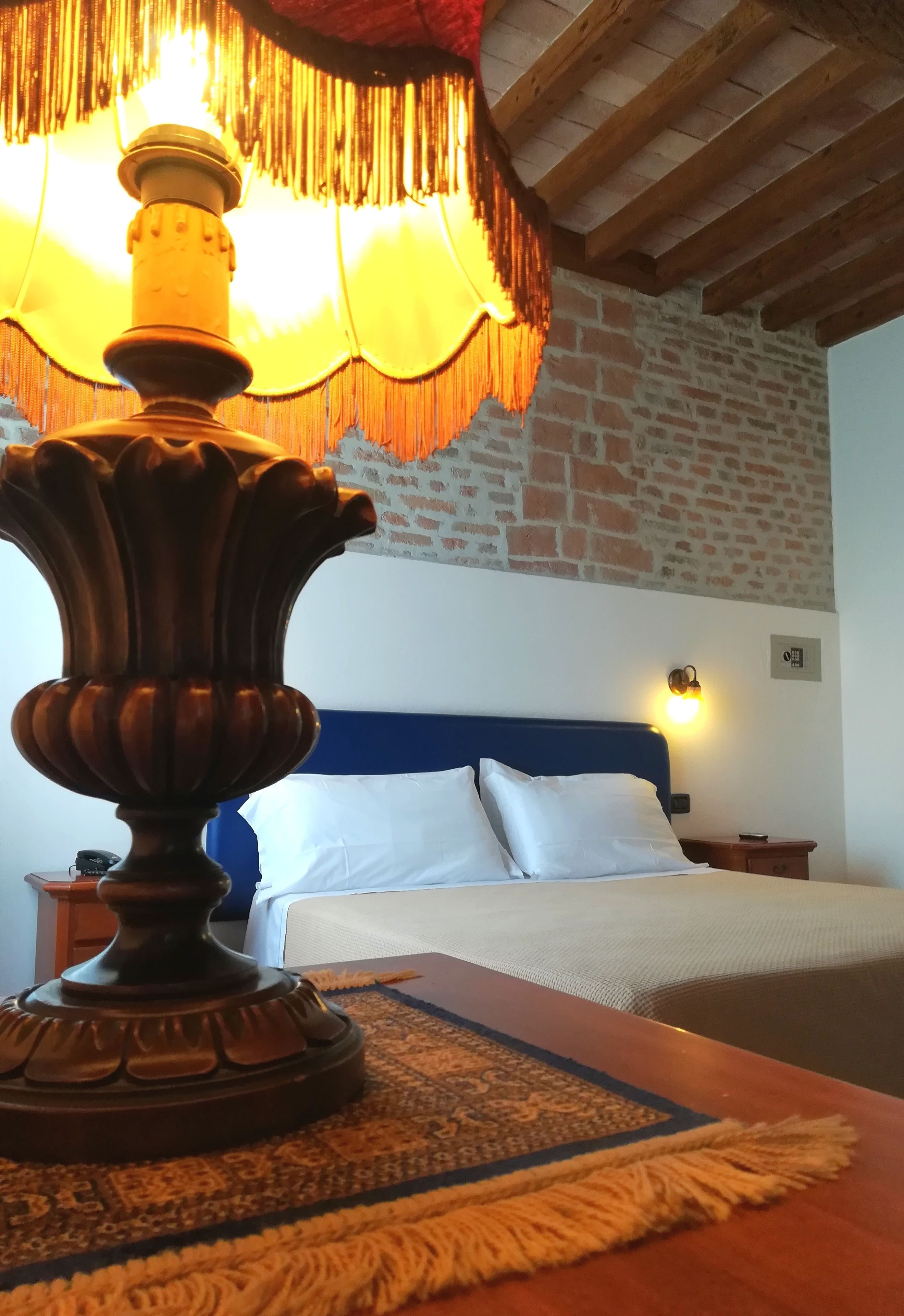 Ein Bett mit weißer Bettwäsche, einem blauen Kopfteil und einer wandmontierten Lampe.