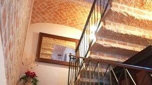 Una escalera con barandilla de metal, pared de ladrillo y un cuadro en la pared.
