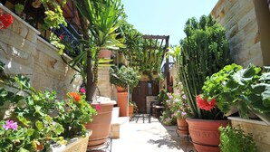 A narrow courtyard with potted plants and a wooden pergola. - Sofia Pension (Rhodes)