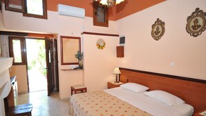A bedroom with a bed, a nightstand, a bedside table, a mirror, and a window. - Sofia Pension (Rhodes)