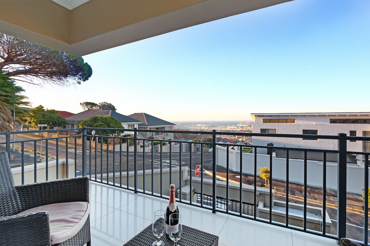 A balcony with wicker furniture, a bottle of champagne, and two glasses.