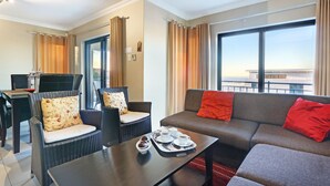 A modern living room with a sofa, two armchairs, a coffee table, and a dining table. - Star Holiday Apartments (Cape Town)