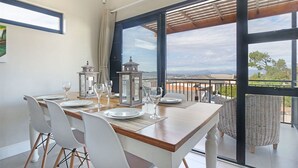 A dining area with a table set for four, large windows offering a view of the cityscape. - Star Holiday Apartments (Cape Town)