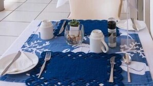 Un espace repas avec des tables dressées pour le repas, un ventilateur de plafond et une vue sur l’extérieur.
