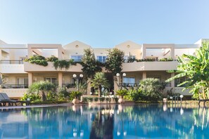 Un hotel con piscina, mobiliario exterior y exuberante jardinería.