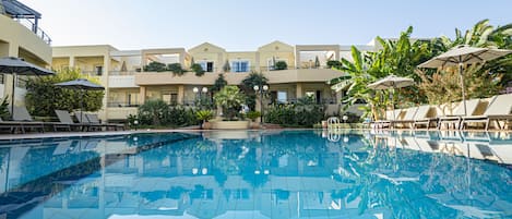 Una piscina al aire libre, sombrillas, sillones reclinables de piscina