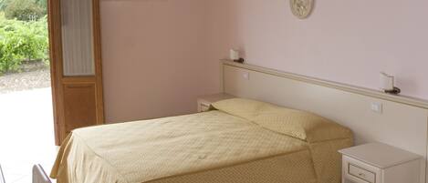 A bedroom with a bed, bedside tables, a chair, and a door leading to a balcony.