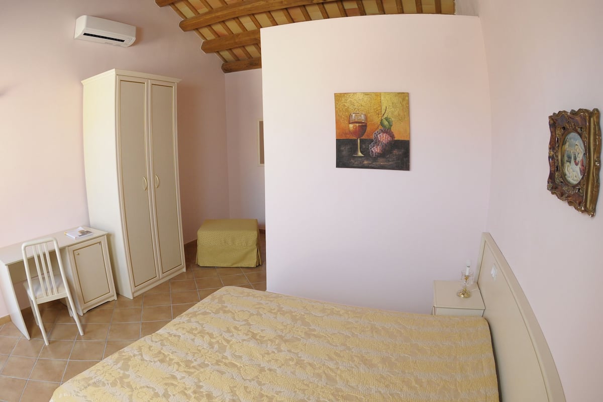A bedroom with a bed, a wardrobe, a desk, and a chair.