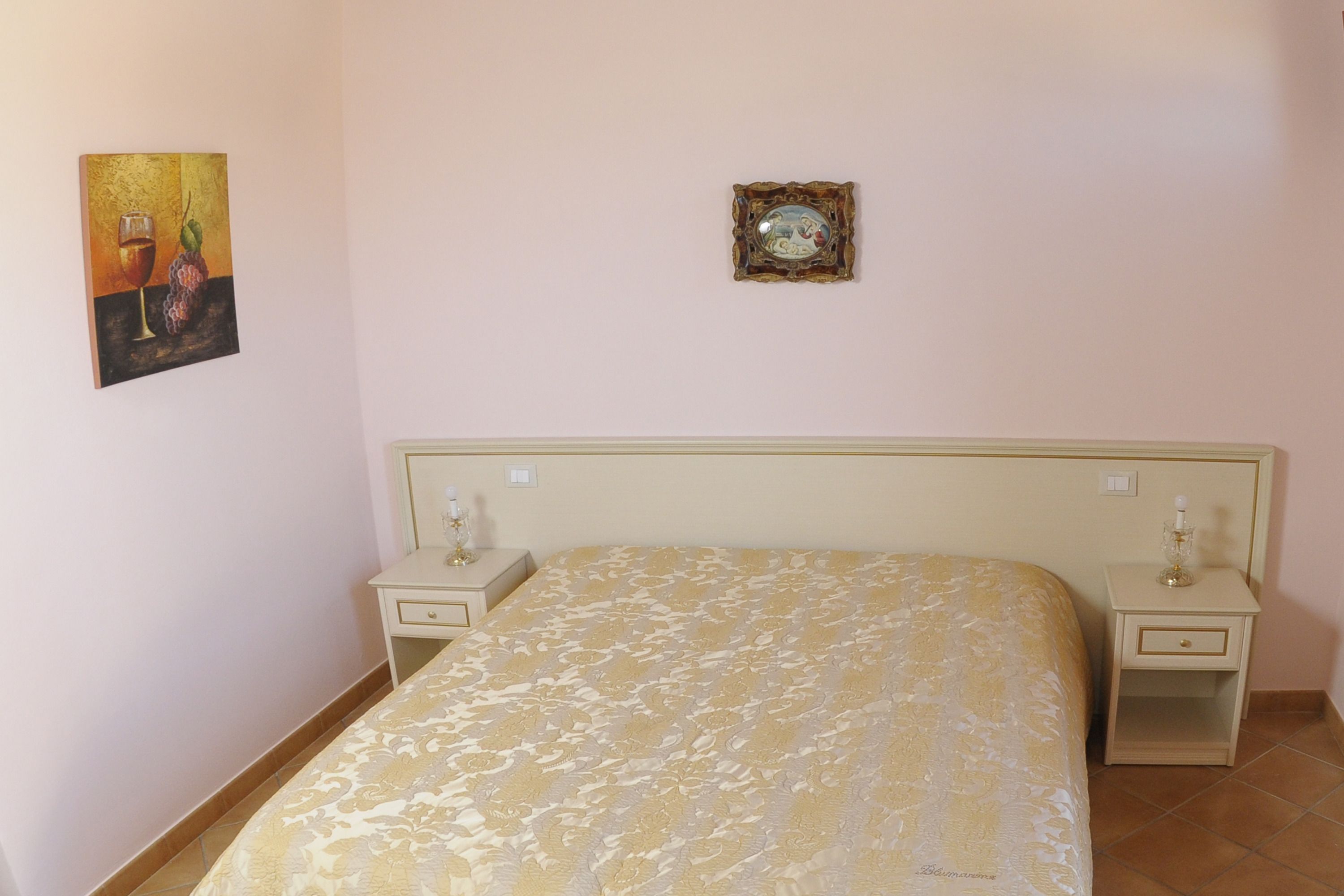 Una camera da letto con un letto, due comodini, un piccolo tavolo e due quadri appesi al muro.