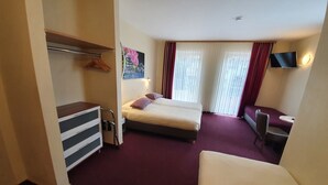 Una habitación de hotel con una cama, un escritorio, una silla y un televisor.