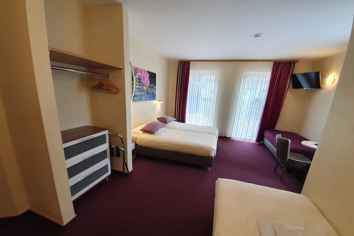 Une chambre d’hôtel avec un lit, un bureau, une chaise et un téléviseur.