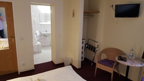 A hotel room with a bed, a small table with a chair, a TV mounted on the wall, and a bathroom visible through an open door. - Hotel Bergschlößchen (Boppard)
