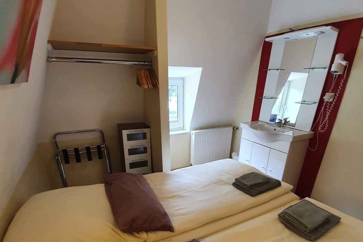 Une chambre d’hôtel avec deux lits, un radiateur, une fenêtre, un miroir et un porte-serviettes.