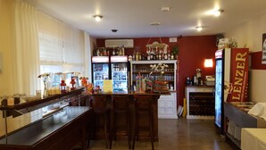 Una zona de bar con sillas de madera, un refrigerador lleno de bebidas y una estantería para vinos.