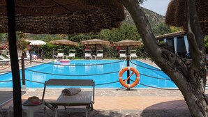 Zona de piscina con sillones de descanso, sombrillas y un flotador salvavidas.