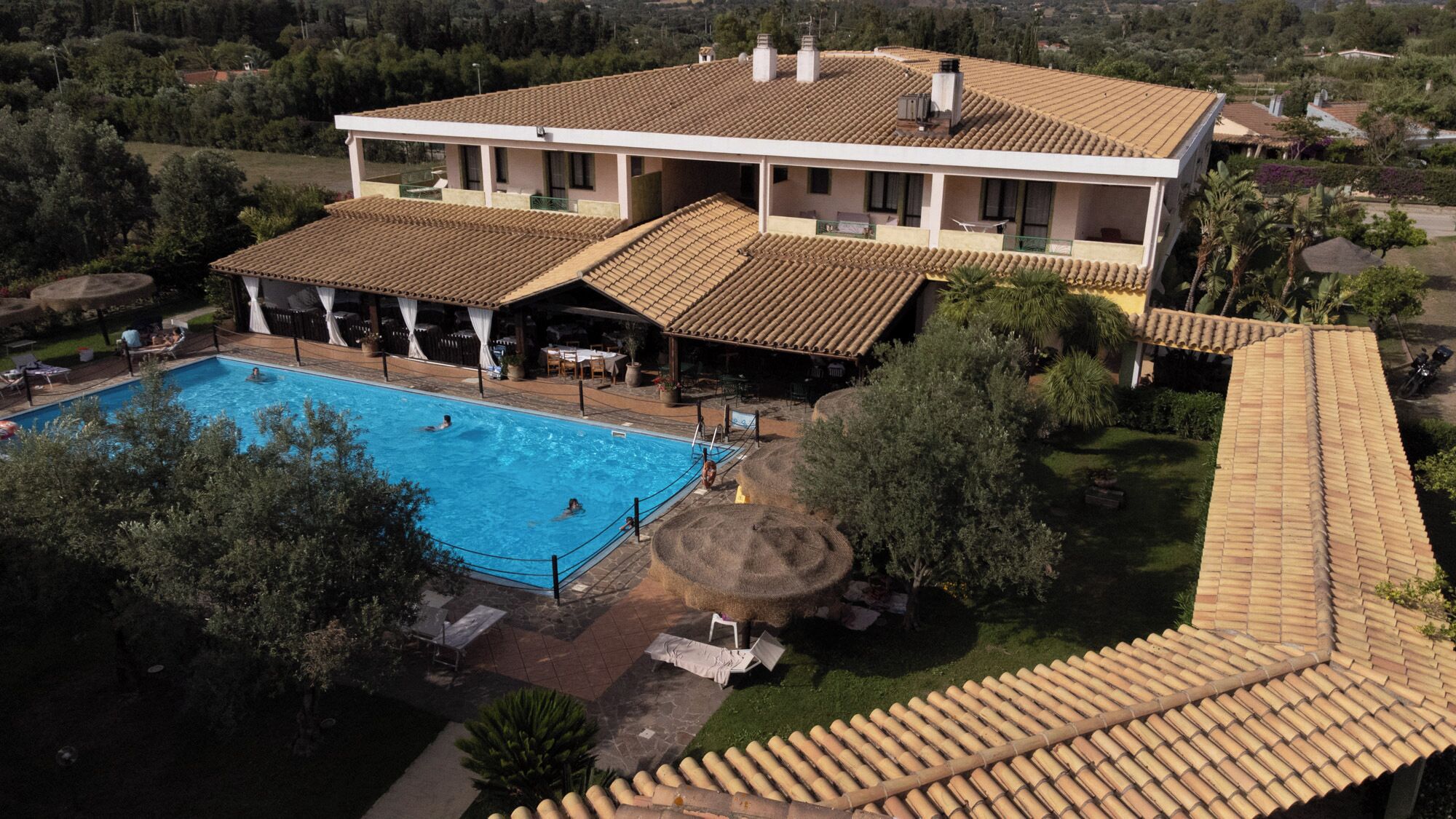 Una casa grande con piscina, terraza cubierta y jardín.