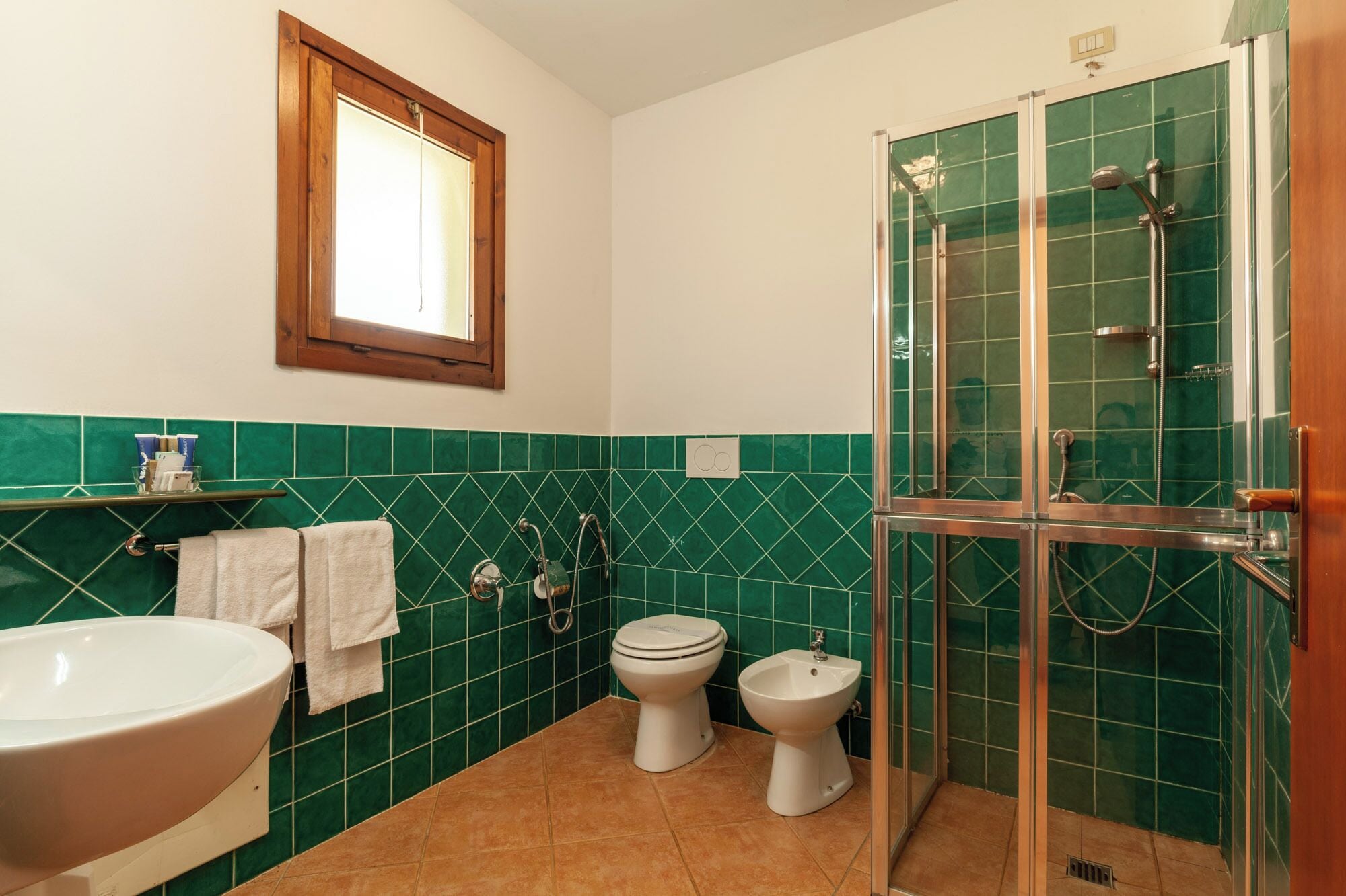 A bathroom with a bathtub, two toilets, a bidet, and a glass-enclosed shower.