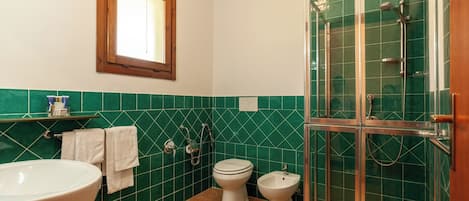 A bathroom with a bathtub, two toilets, a bidet, and a glass-enclosed shower.