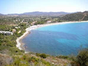 A coastal landscape with a beach, clear blue waters, and a hilly backdrop. - iH Hotels Villasimius Le Zagare Resort (Villasimius)