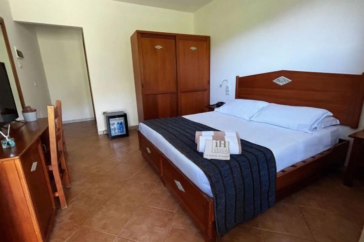 A bedroom with a wooden bed, a desk, and a wardrobe.