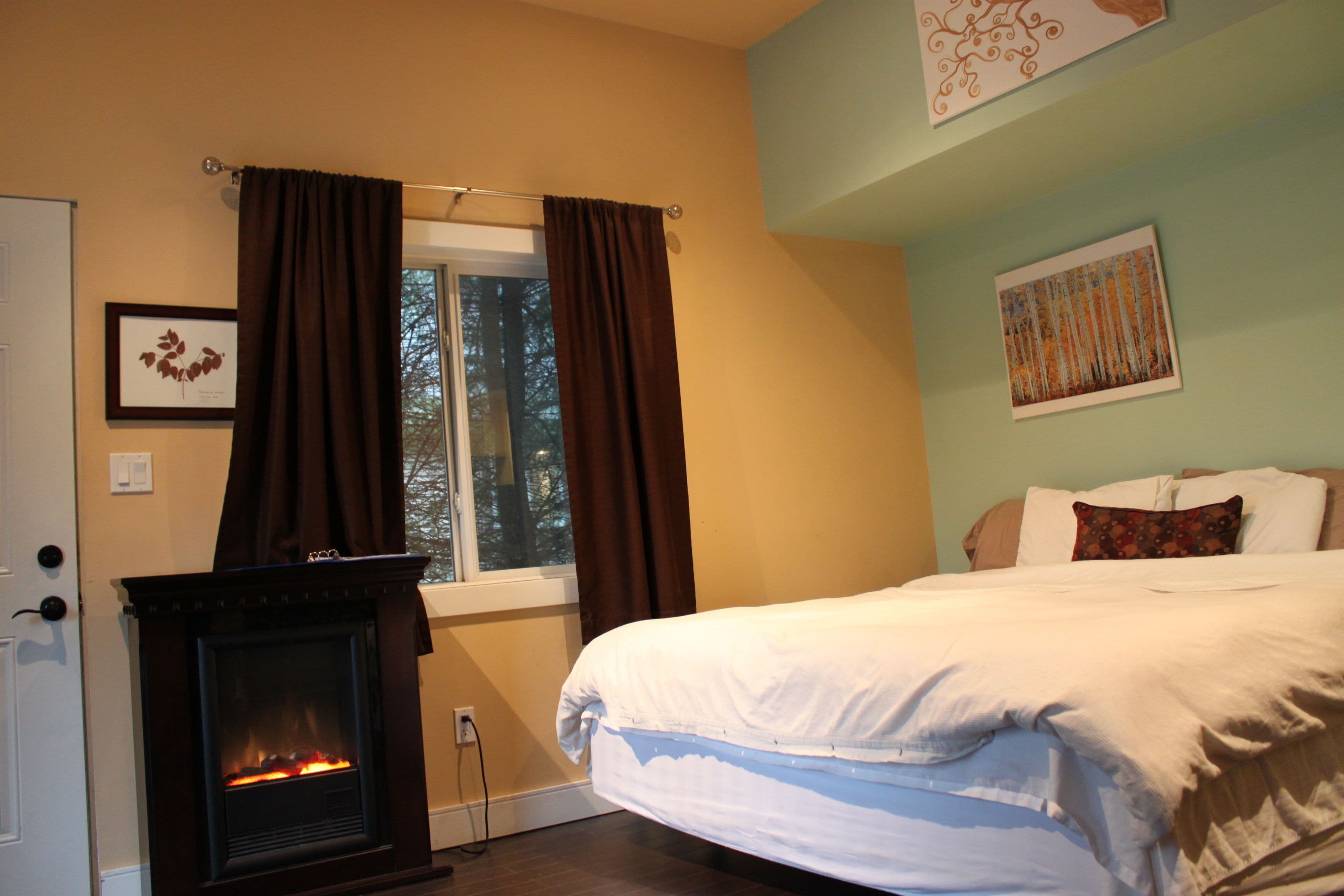 A bedroom with a fireplace, a bed, and a window with curtains.