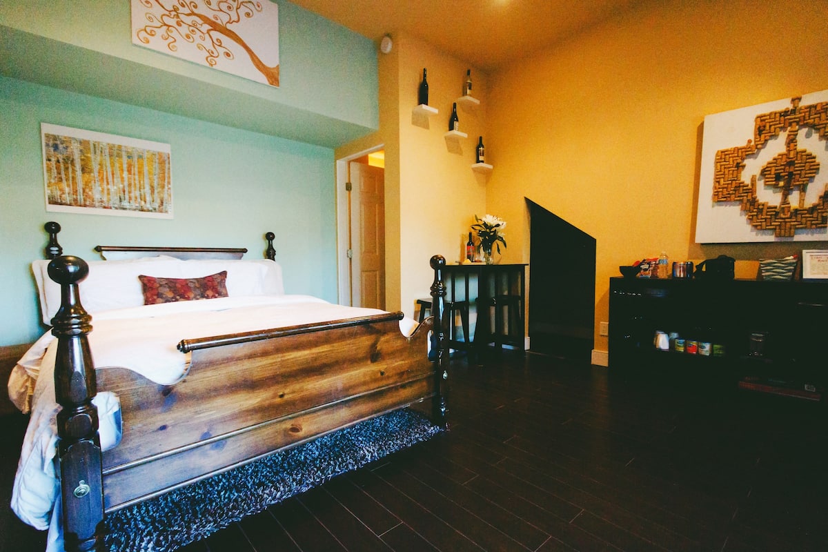 Ein Schlafzimmer mit einem hölzernen Bett, einem kleinen Tisch mit einer Vase und einer Treppe, die in einen anderen Raum führt.
