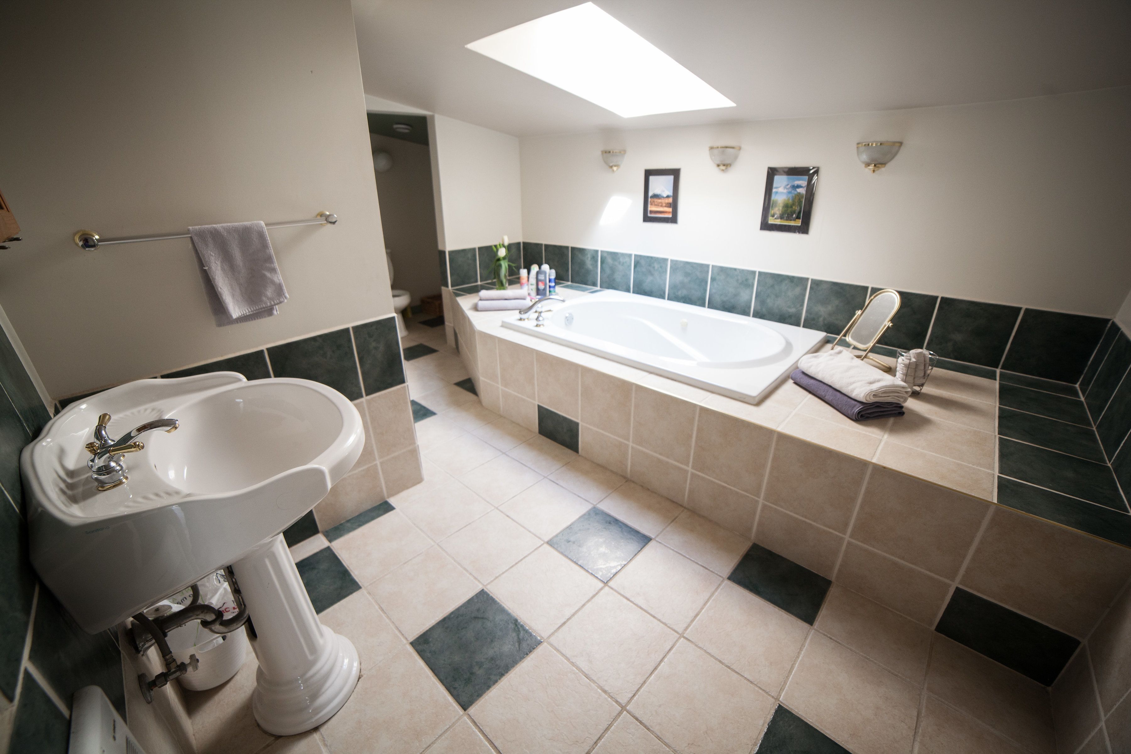 A bathroom with a sink, bathtub, and two framed pictures on the wall.