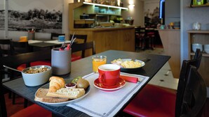 Ambiente de café da manhã com uma mesa, cadeiras e uma cozinha ao fundo.