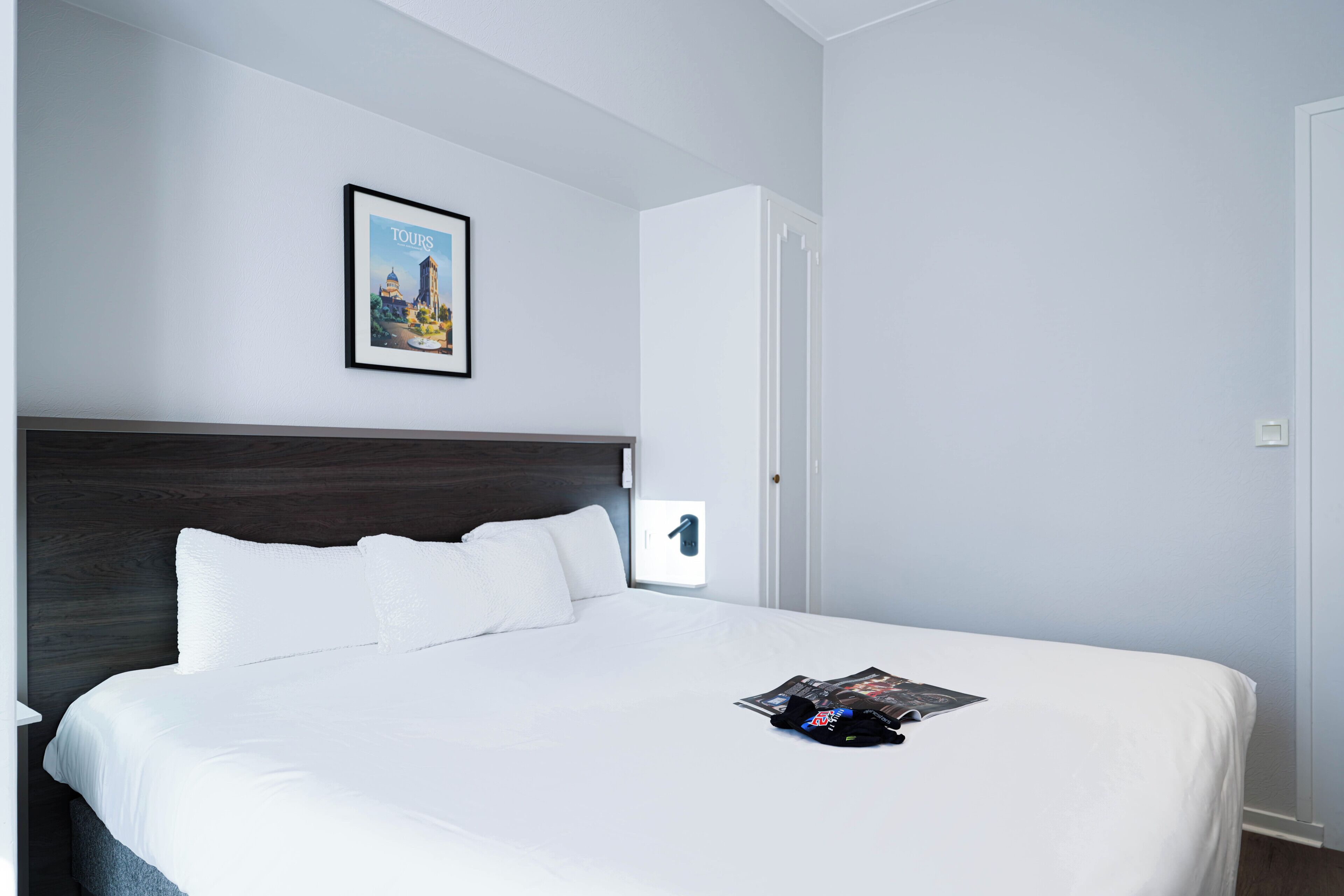 Una camera d'albergo con un letto grande, un quadro appeso al muro e una porta.