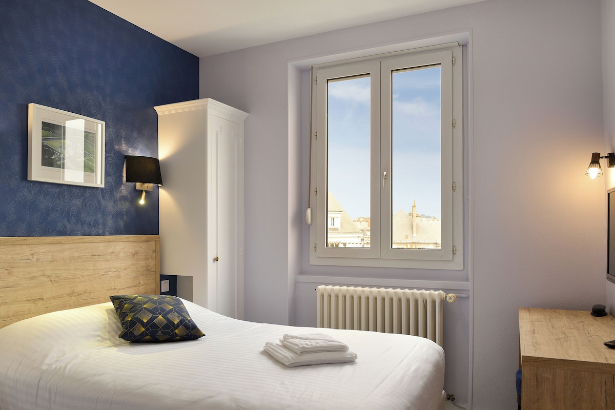 Ein Schlafzimmer mit Bett, Fenster, Heizkörper und Nachttisch.