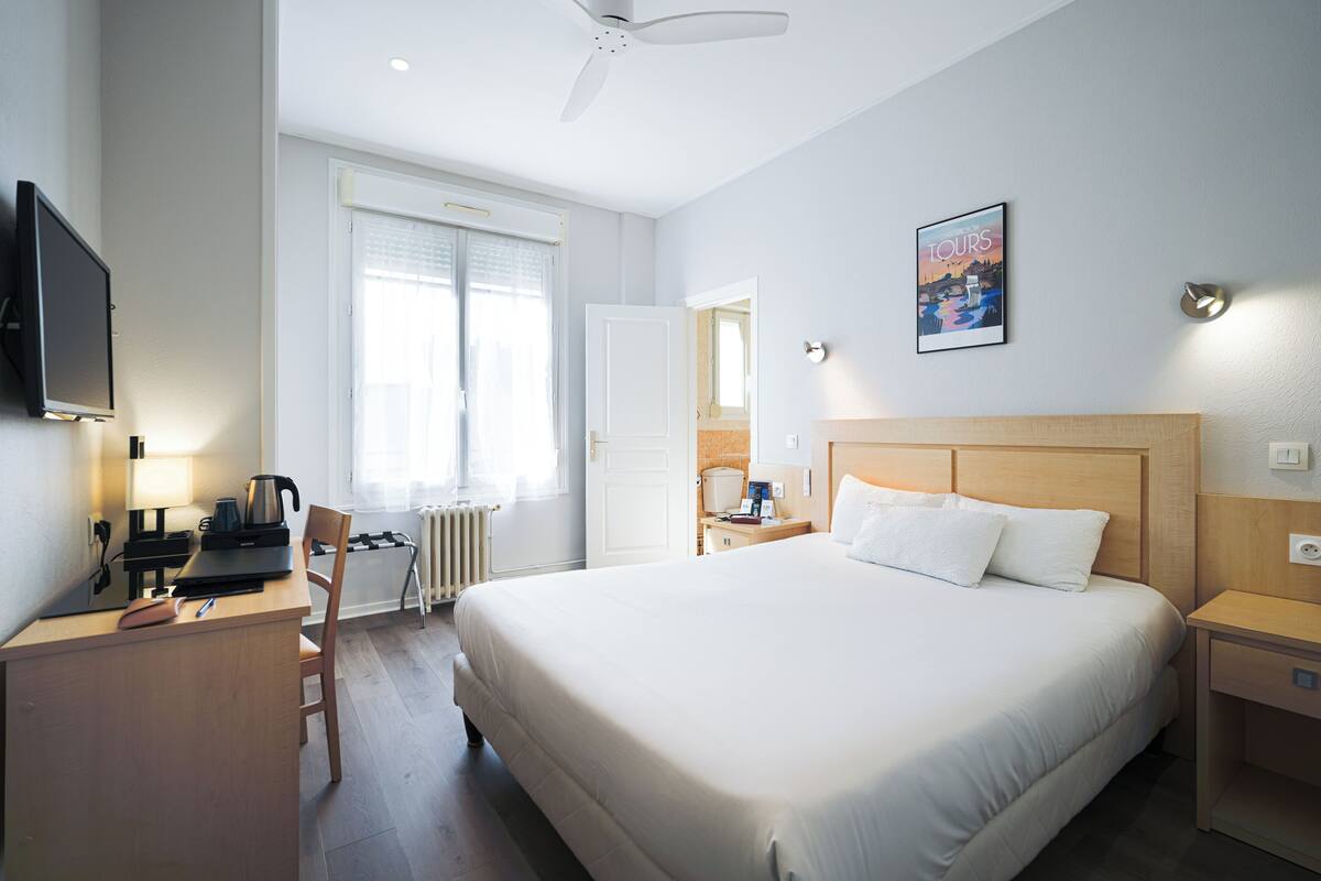 Une chambre d’hôtel équipée d’un lit, d’un bureau, d’une chaise et d’un téléviseur.