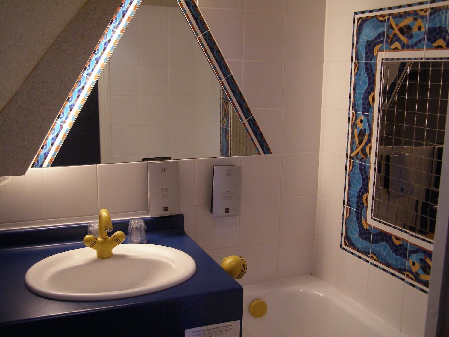 A bathroom with a sink, mirror, and bathtub.