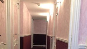 Un couloir étroit aux murs roses et recouvert d’une moquette sombre.