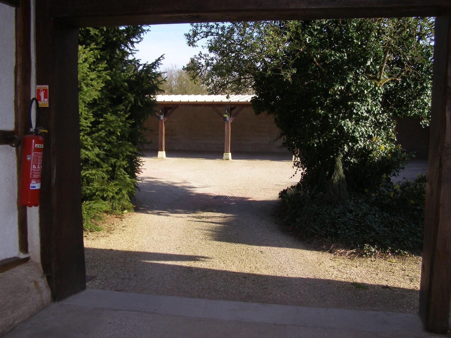 Una entrada a un edificio con un camino de grava que lleva a un área cubierta con columnas.