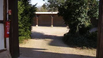 Una entrada a un edificio con un camino de grava que lleva a un área cubierta con columnas.