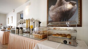 A buffet setup with various food items, including bread and pastries, and a coffee station. - Hotel Katerina (Naxos)