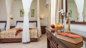 A hotel room with a bed, a bedside table with a book and fruit, and a mirror. - Hotel Katerina (Naxos)