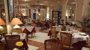 Comedor con mesas dispuestas para el servicio, sillas y una araña.