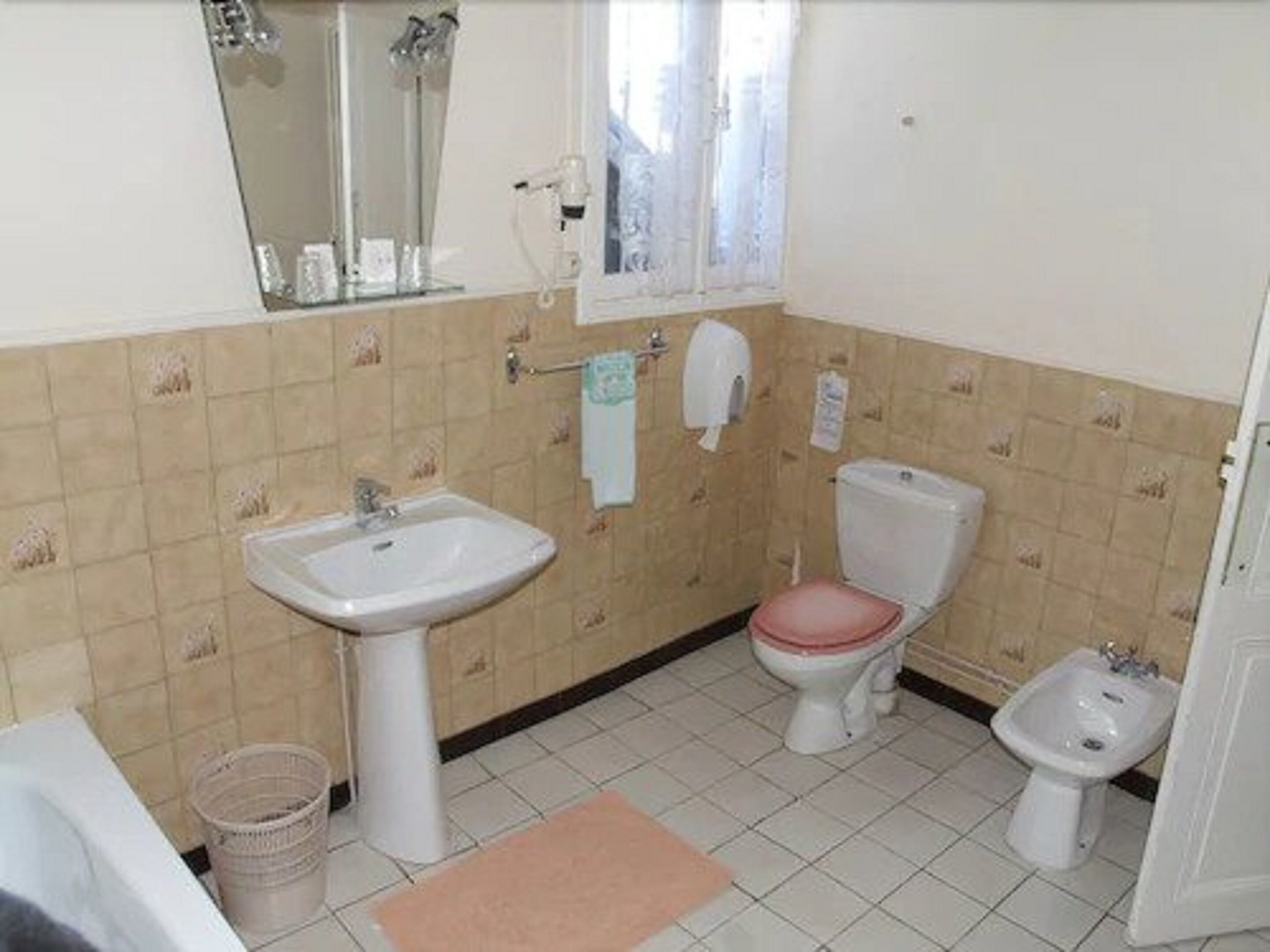 Une salle de bain équipée d’un lavabo, de toilettes, d’un bidet et d’un miroir.