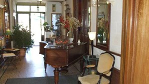 Una habitación con un escritorio de madera, una silla, una lámpara y un espejo. Hay una planta en maceta y una alfombra en el suelo.