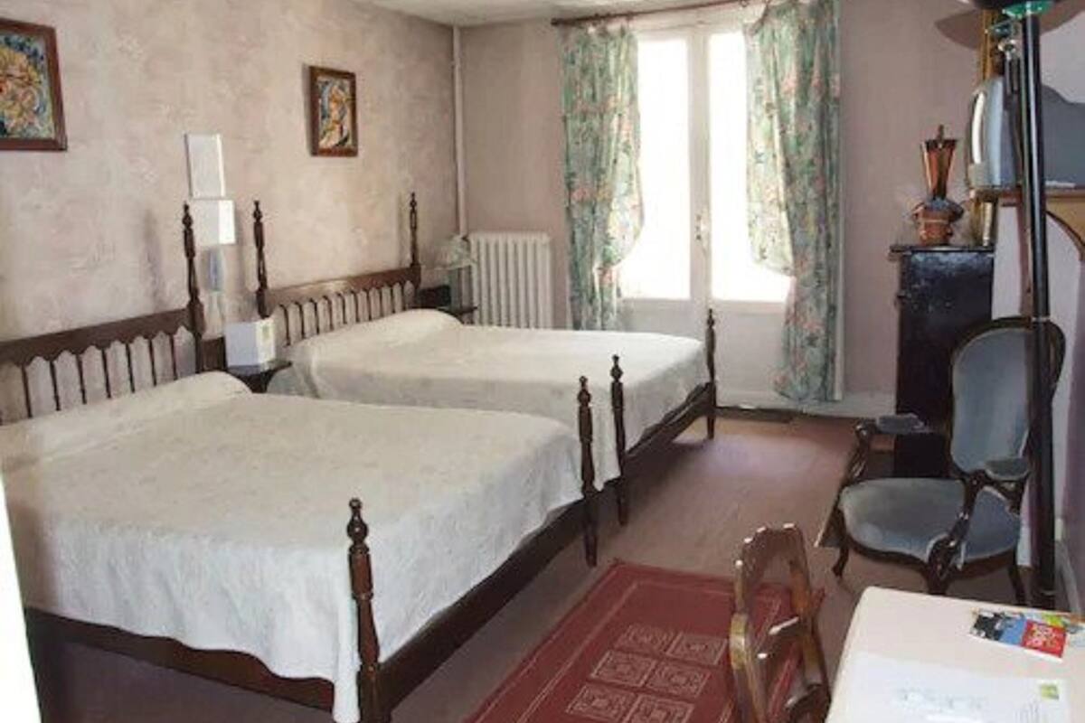 Ein Zimmer mit zwei Einzelbetten, einem Sessel, einem Schreibtisch und einer Heizung.