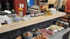 A buffet with various food items, including bread, pastries, and condiments.