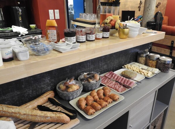 A buffet with various food items, including bread, pastries, and condiments.