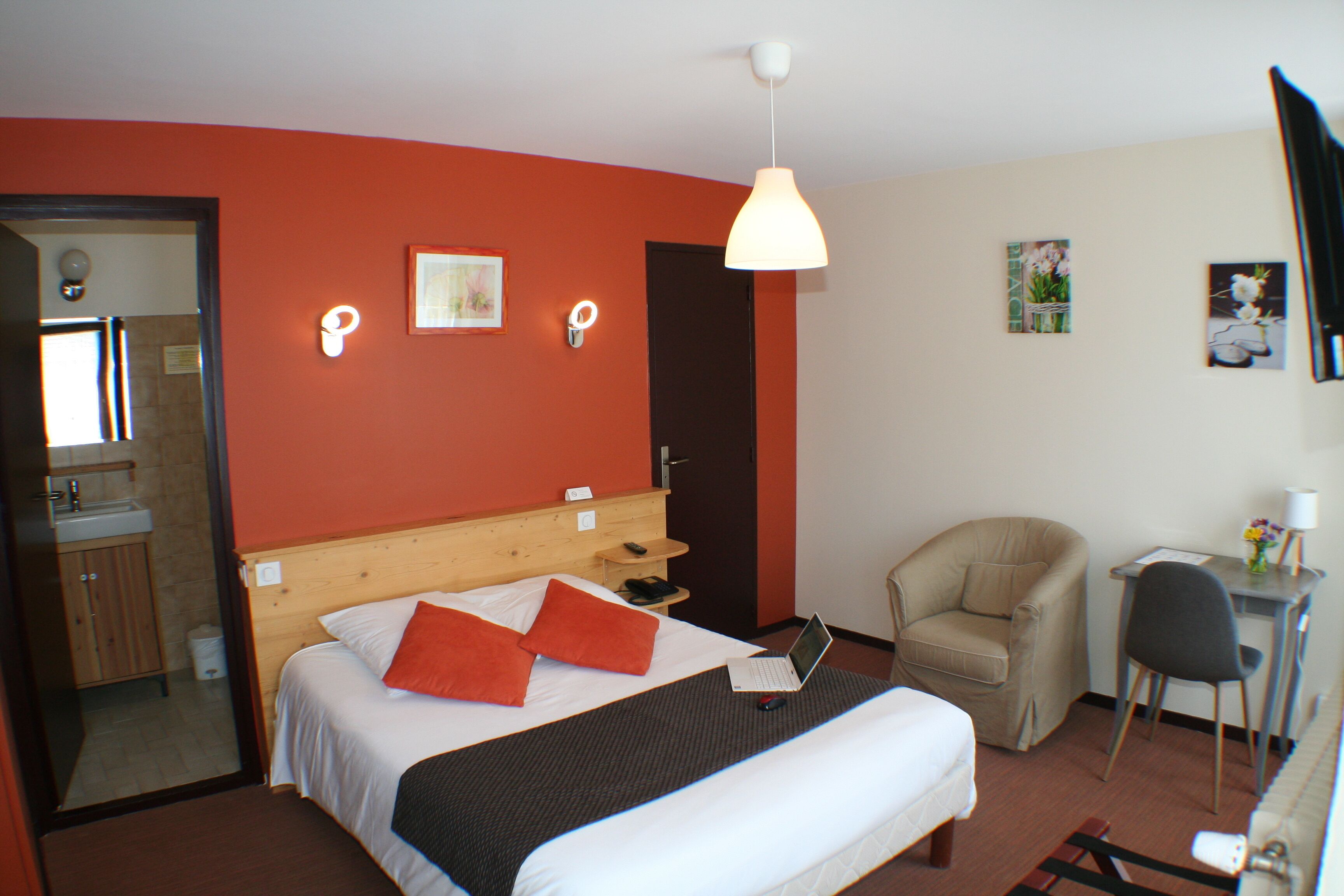 A hotel room with a bed, a chair, a desk, and a mirror.