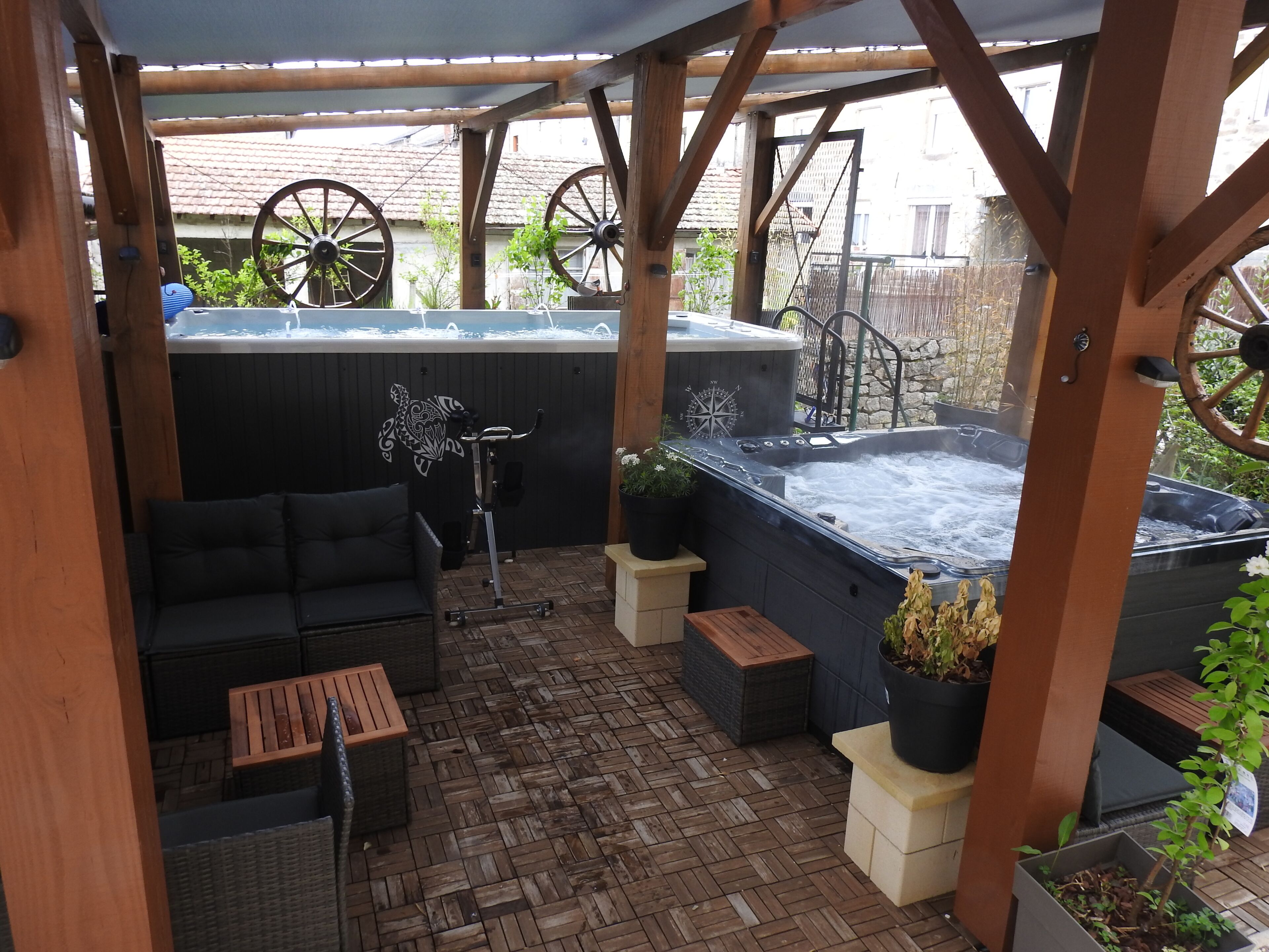Un patio techado con un jacuzzi, zona de estar y equipo de ejercicios.